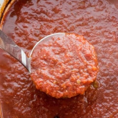 tomato sauce in the crockpot with a latel scooping some up.