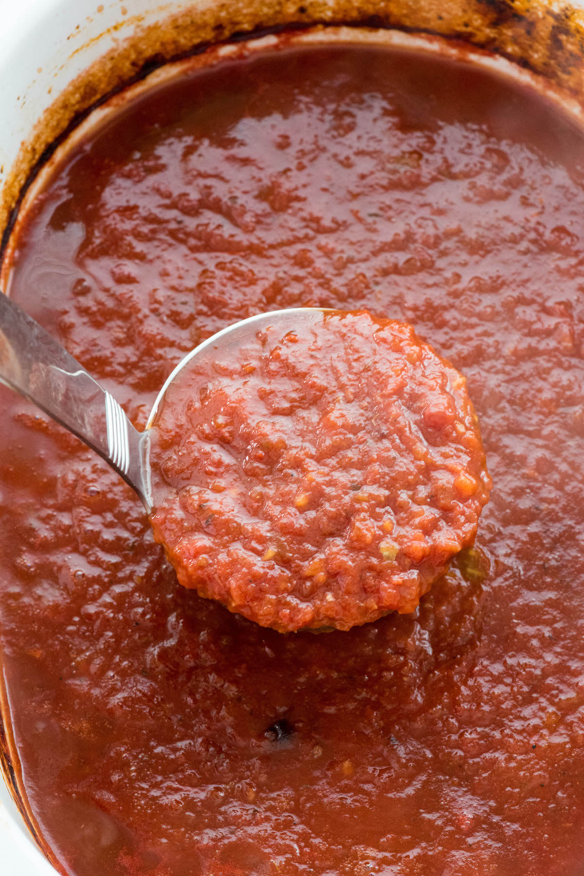 tomato sauce in the crockpot with a latel scooping some up.