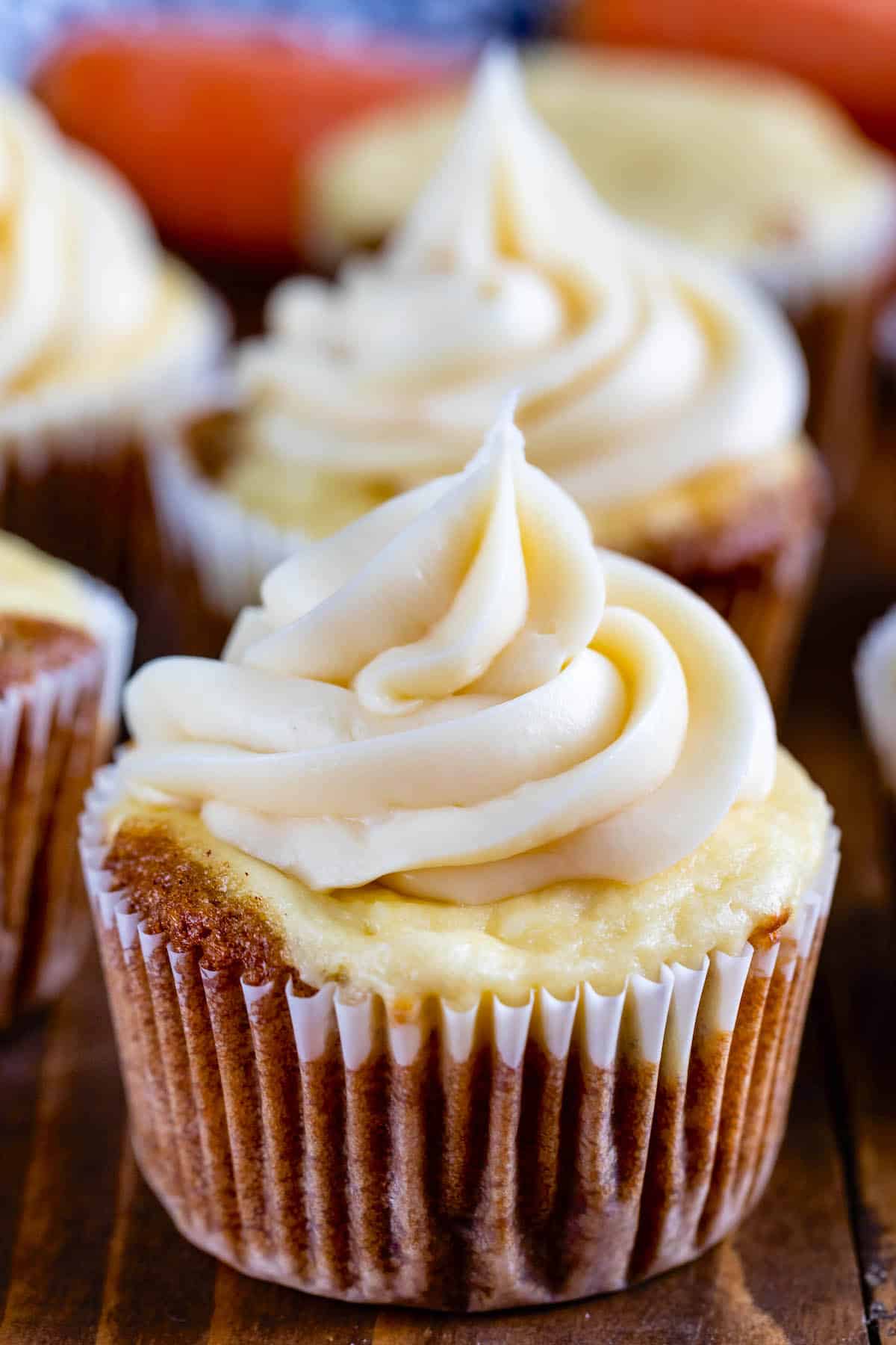 cupcakes with tan frosting on a cutting board.