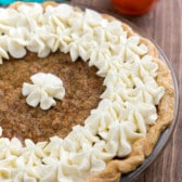 carrot cake pie covered in white frosting in a clear pan.