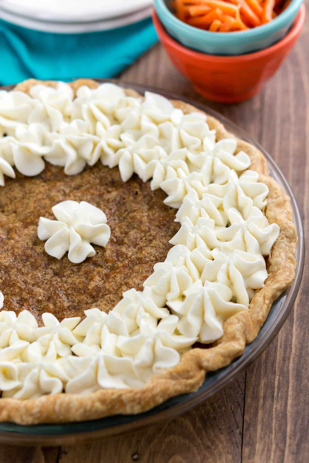 carrot cake pie covered in white frosting in a clear pan.