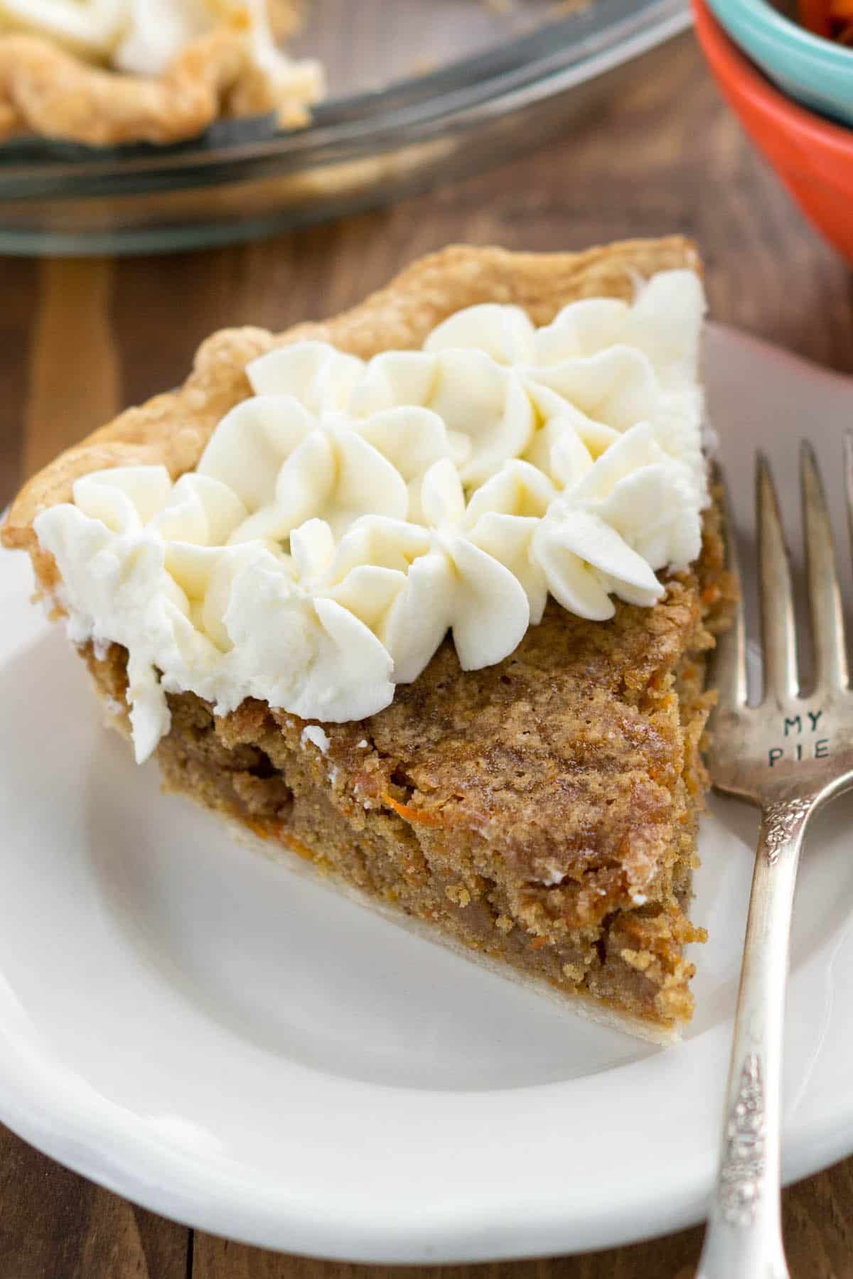 slice of carrot cake pie covered in white frosting on a white plate.