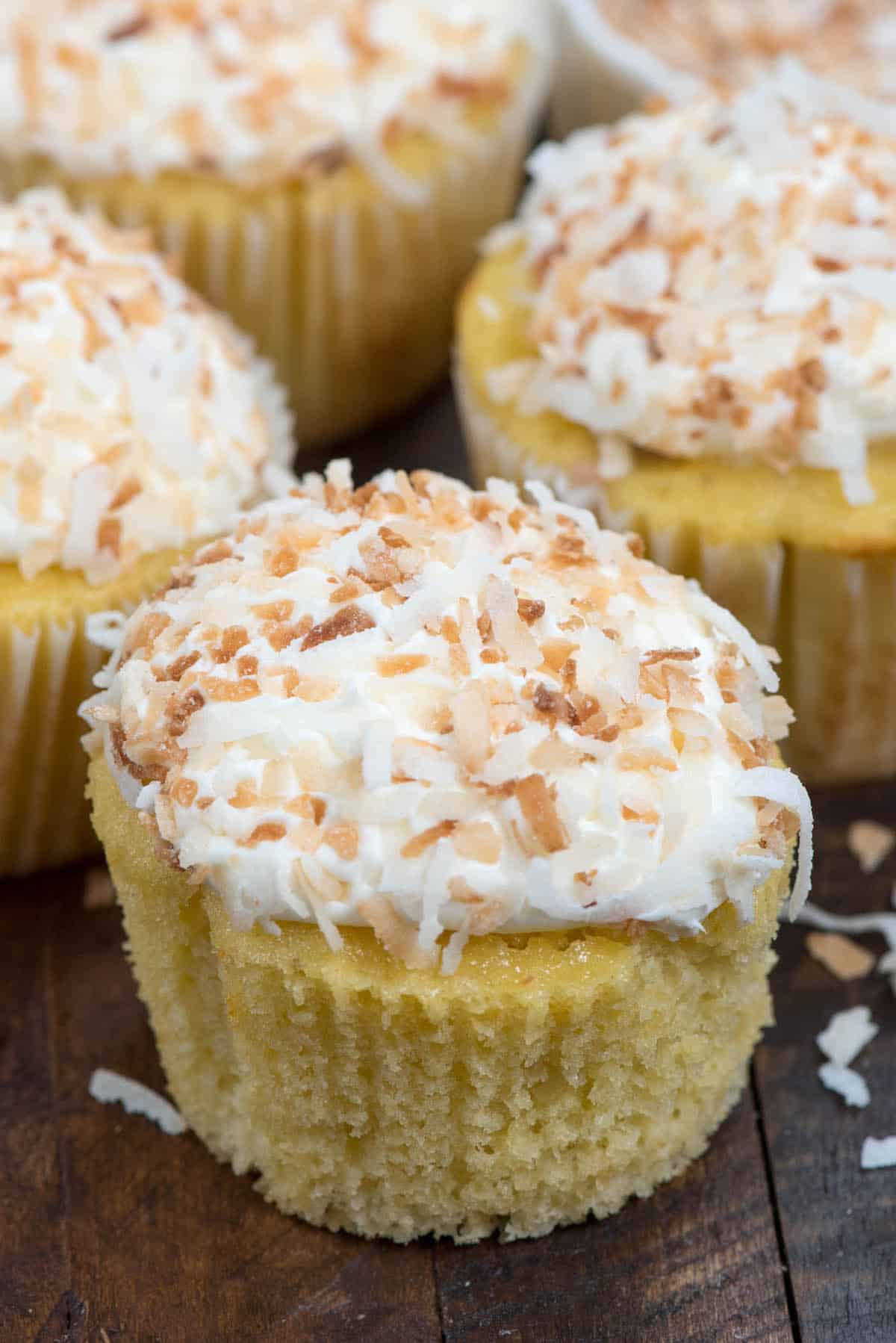yellow cupcakes with white frosting topped with coconut.