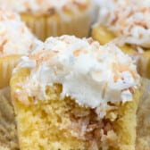 yellow cupcakes with white frosting topped with coconut.