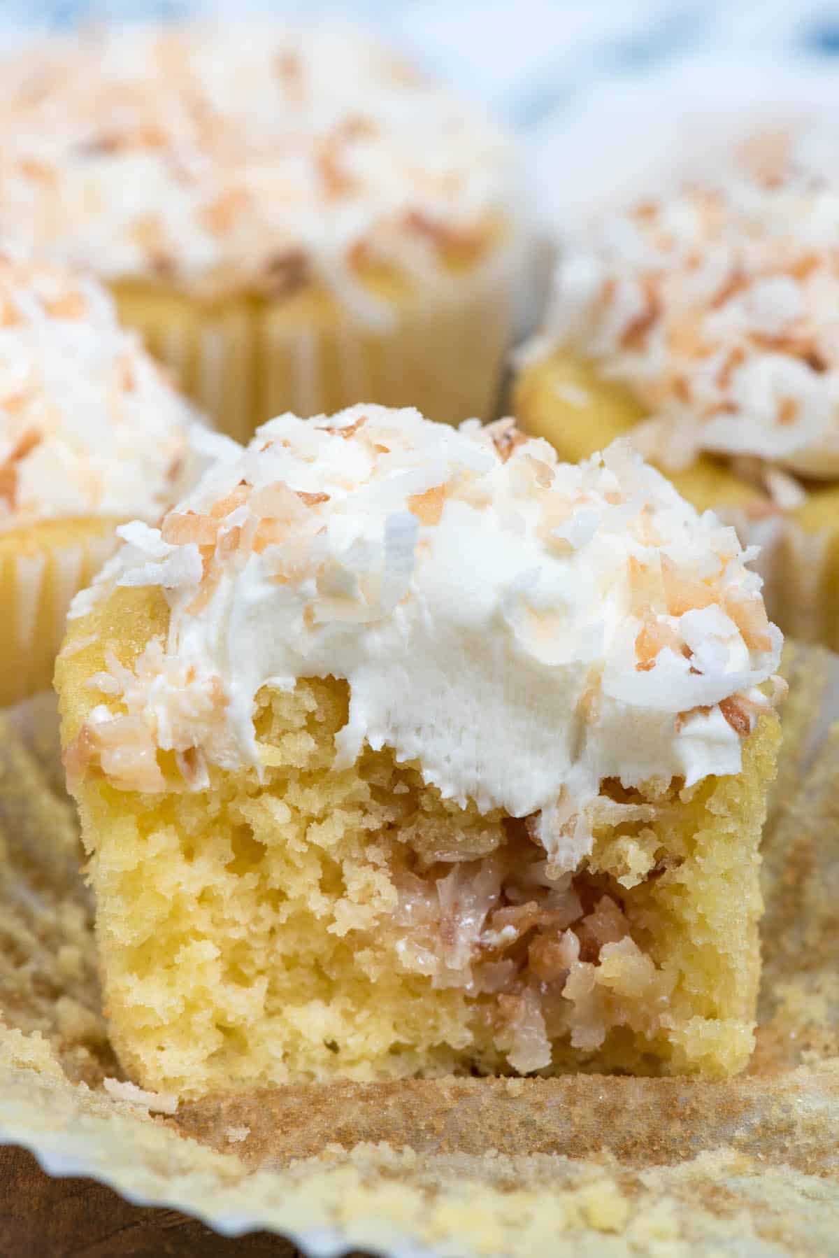 yellow cupcakes with white frosting topped with coconut.