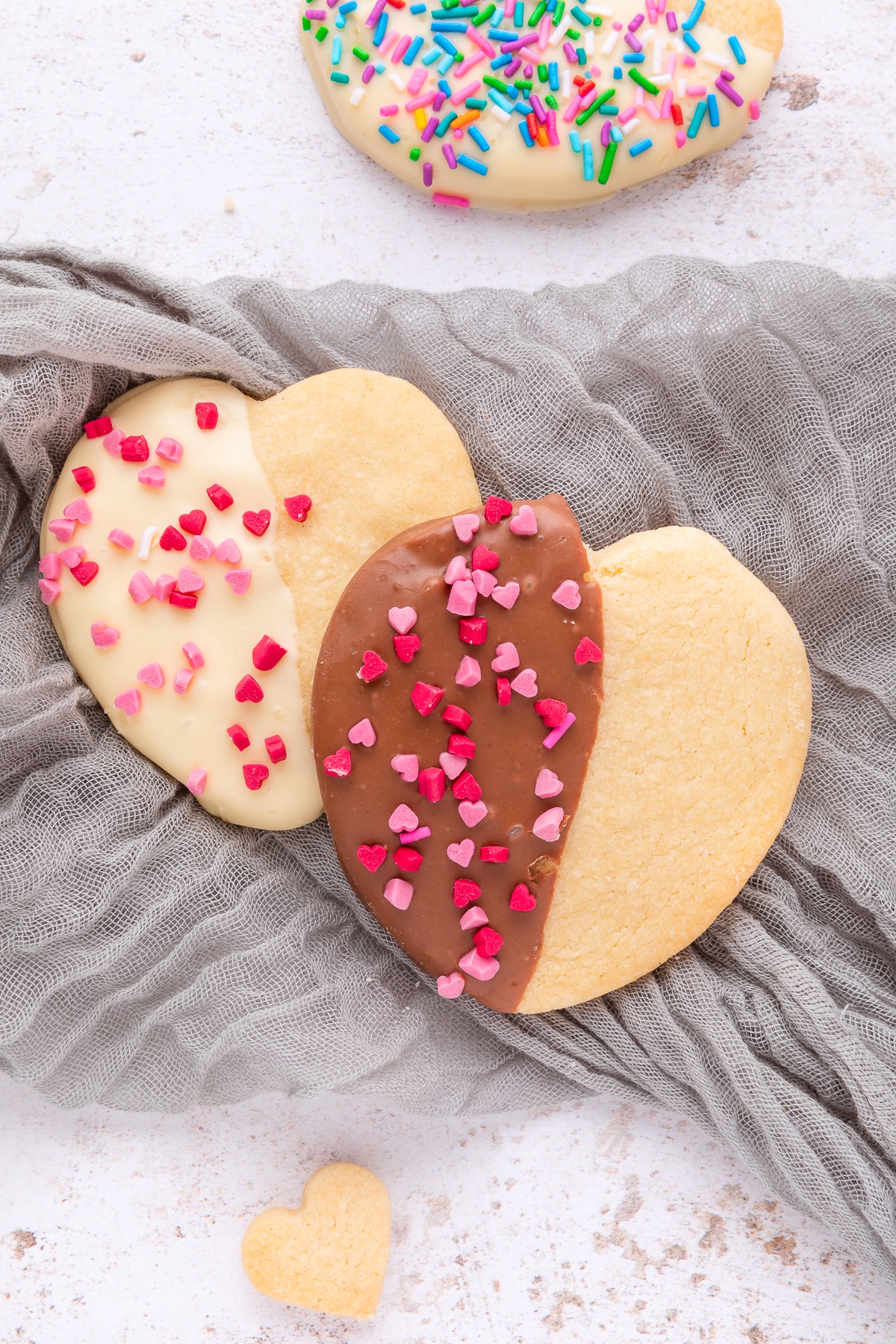 heart shaped cookies half covered in chocolate and sprinkles.