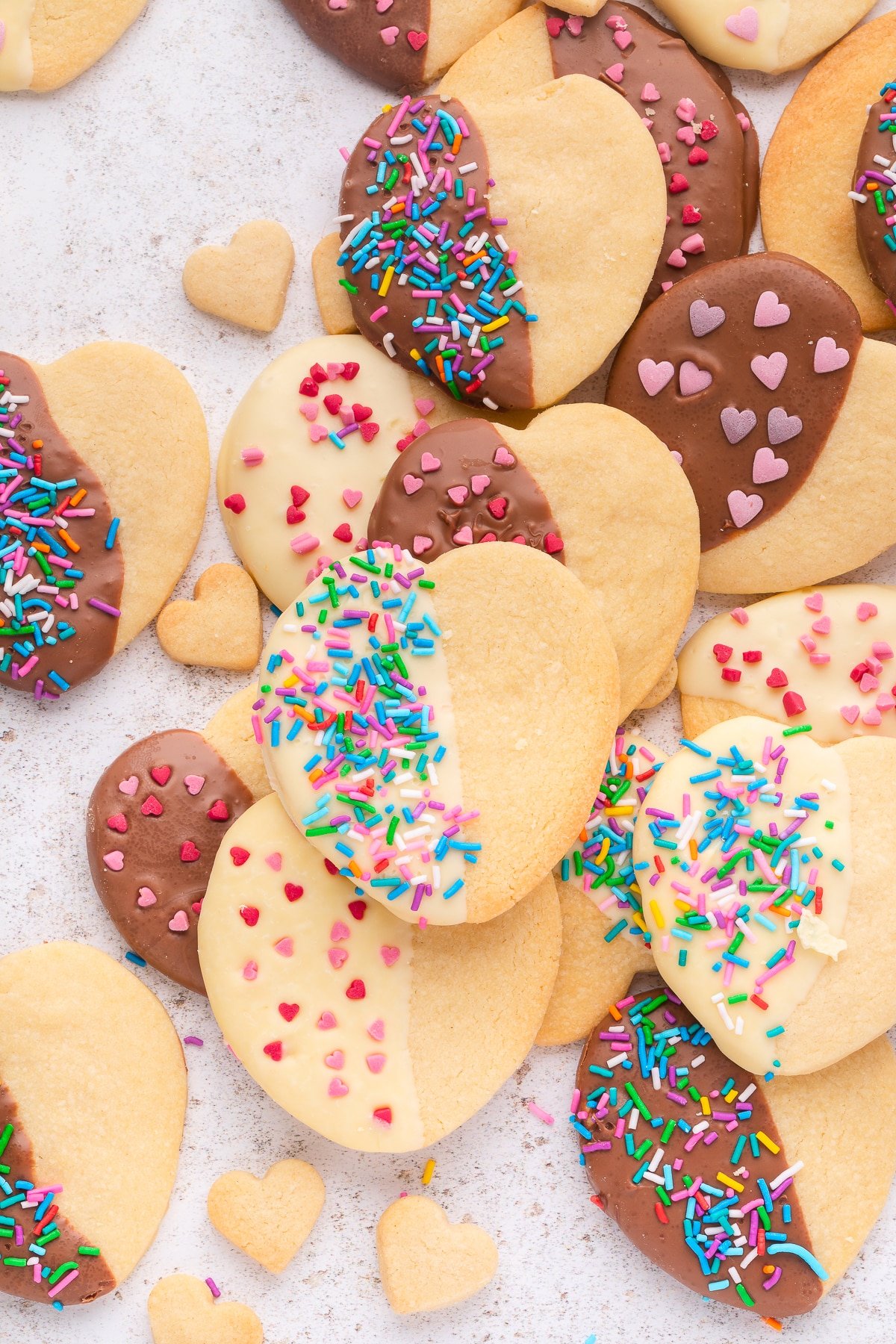heart shaped cookies half covered in chocolate and sprinkles.