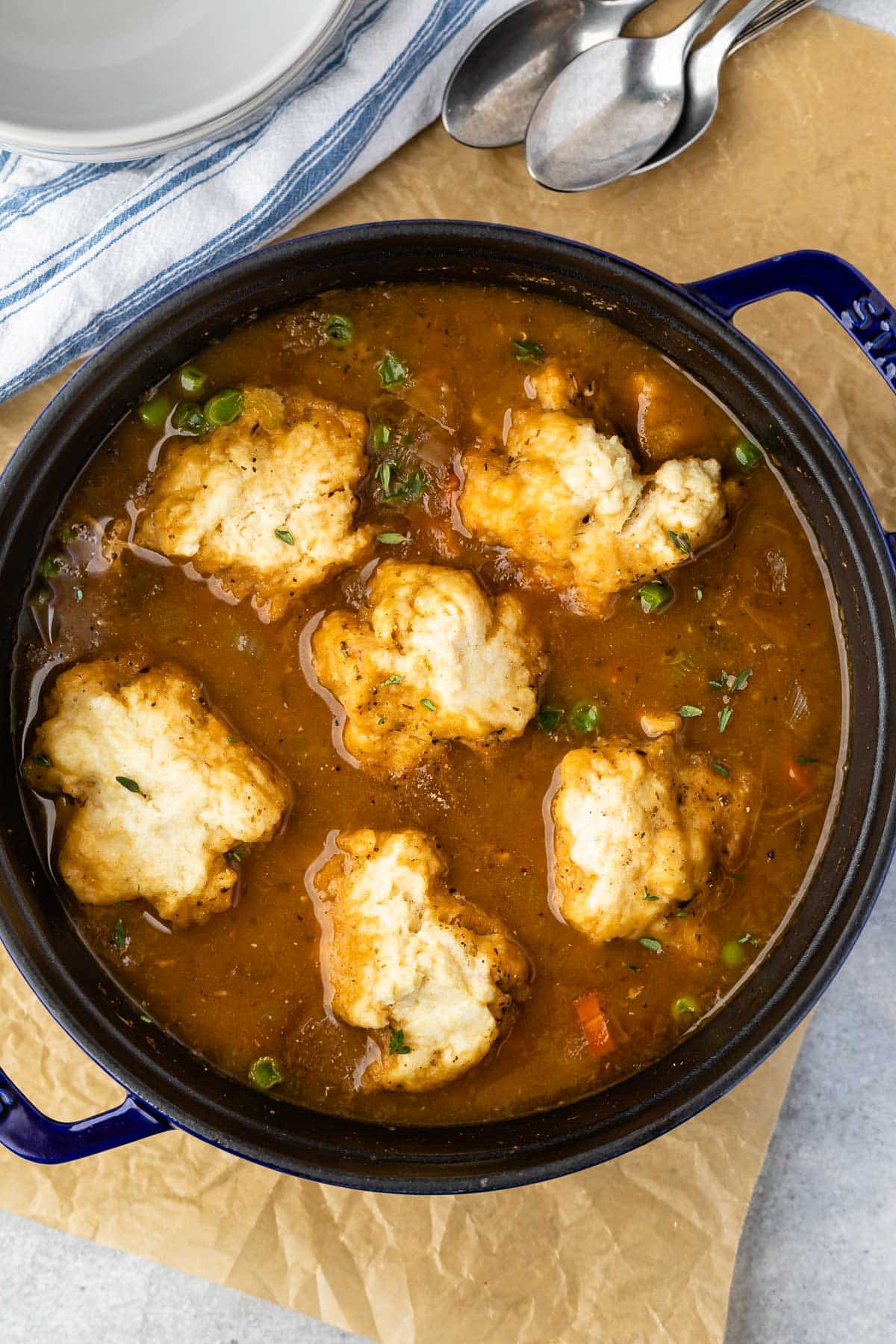 chicken and dumplings in brown soup in a black bowl.