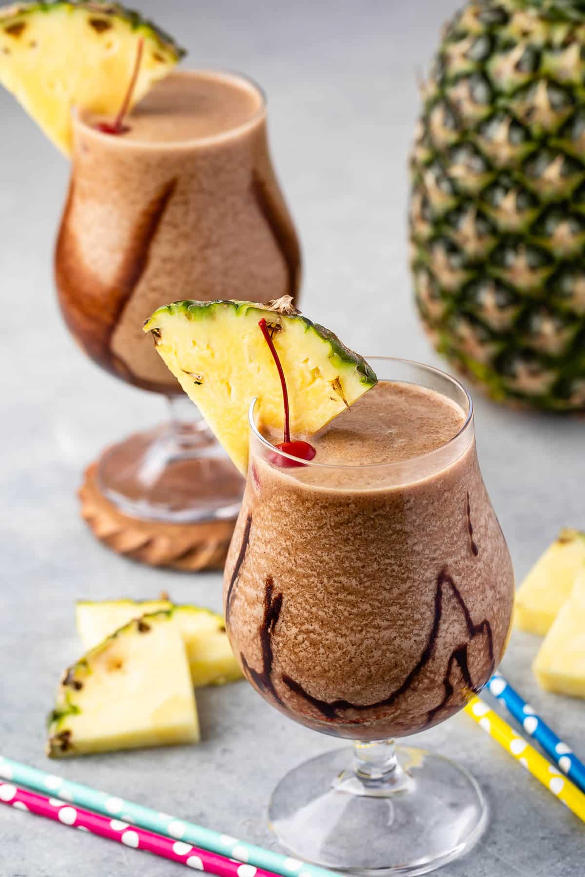 chocolate pina colada in a clear glass with a pineapple and cherry on the rim.