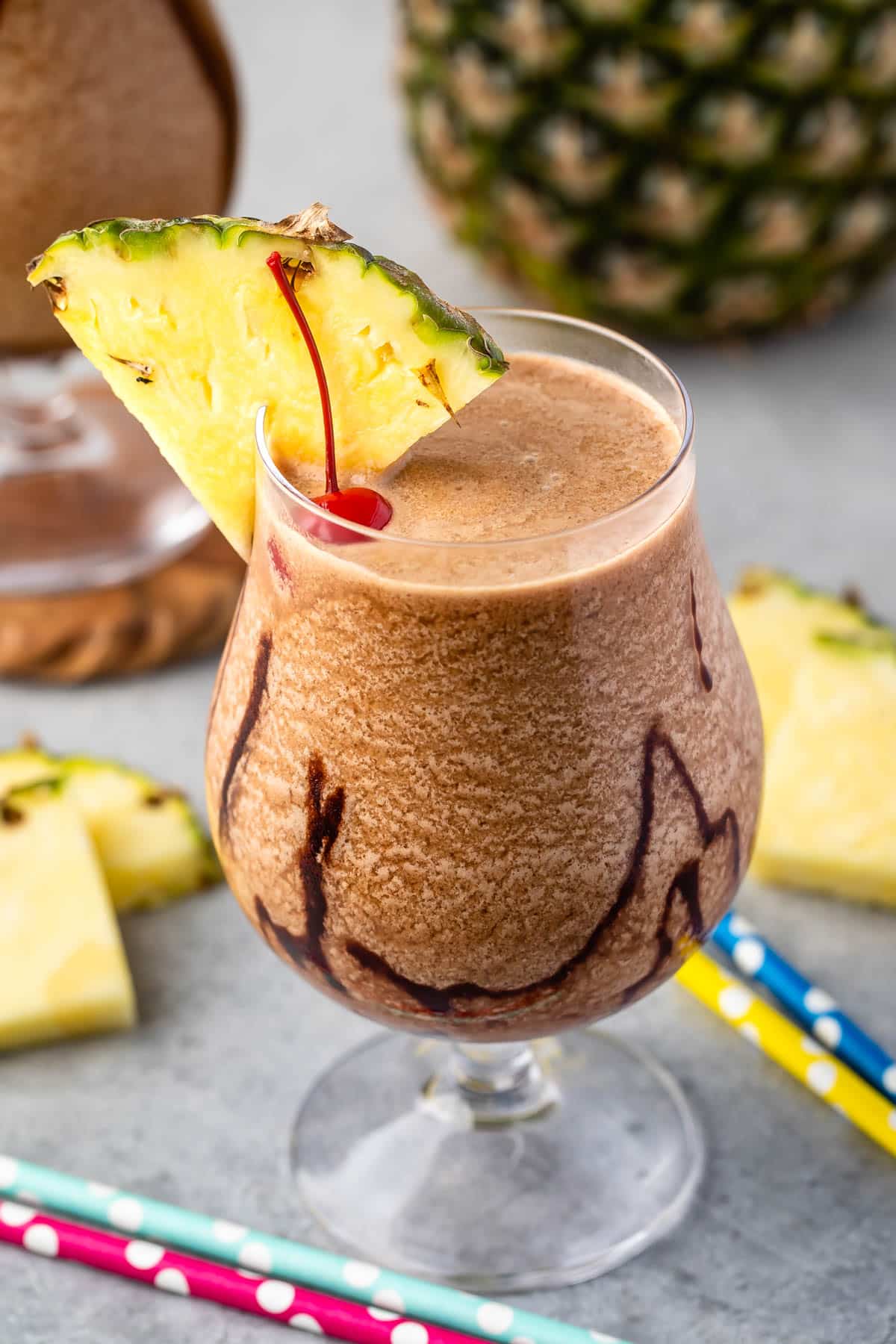 chocolate pina colada in a clear glass with a pineapple and cherry on the rim.