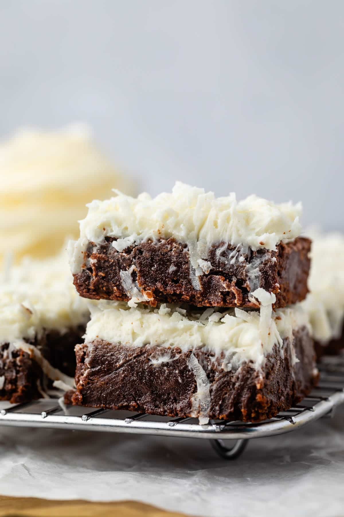 stacked brownies with white frosting mixed with coconuts.