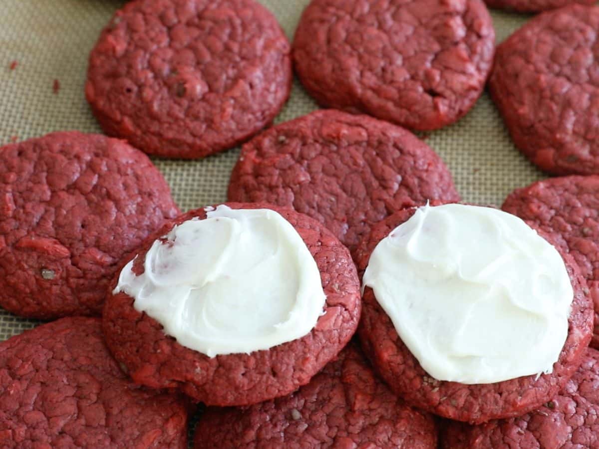 red velvet cookies in a stack with 2 having frosting.