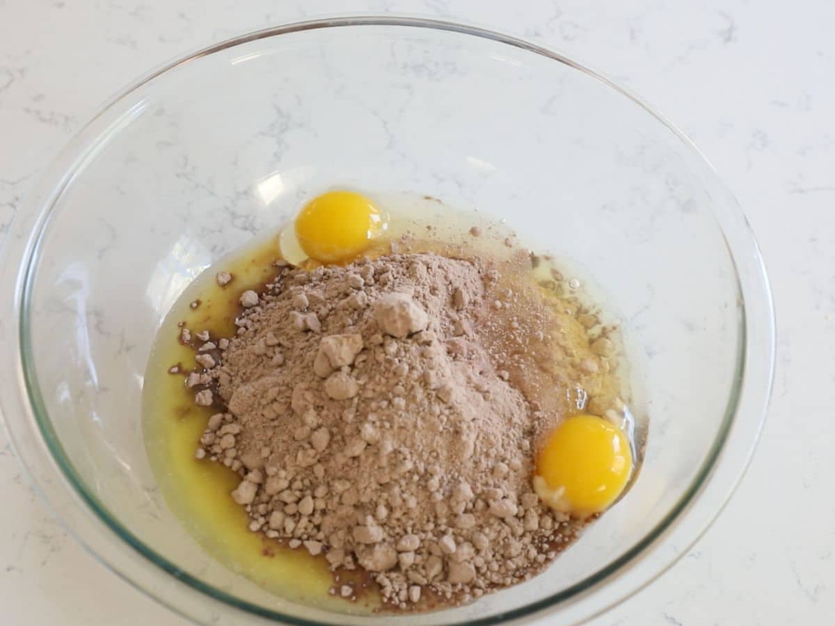 melted butter, cake mix, and eggs in clear bowl.