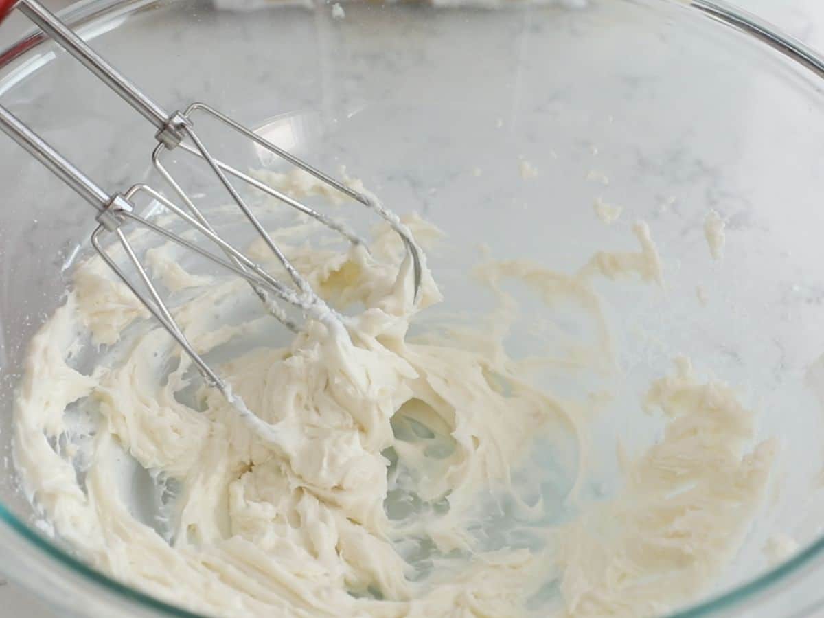 frosting in glass bowl with hand mixer.