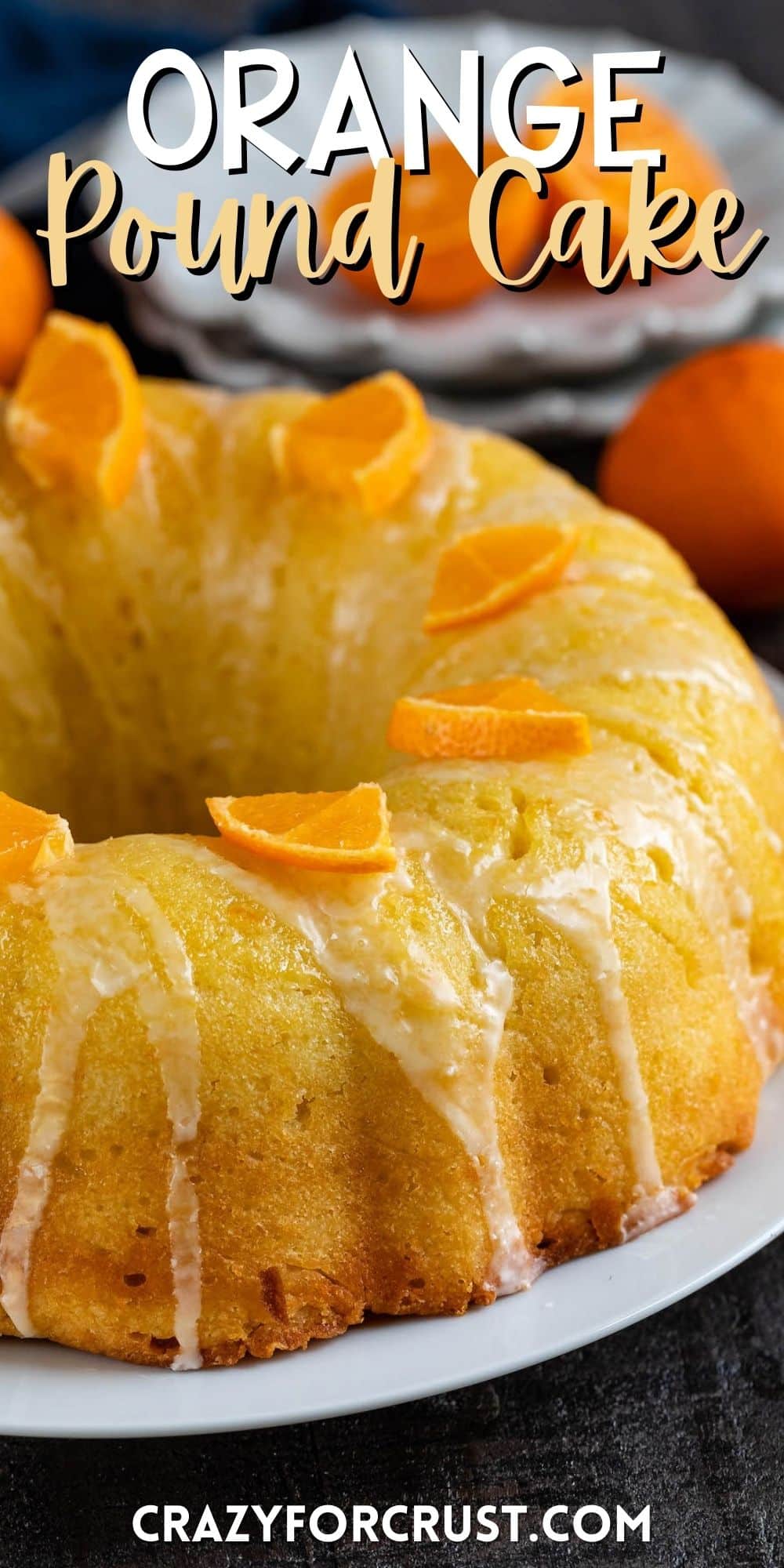 orange bundt cake with sliced oranges and icing on top on a white plate with words on the image.