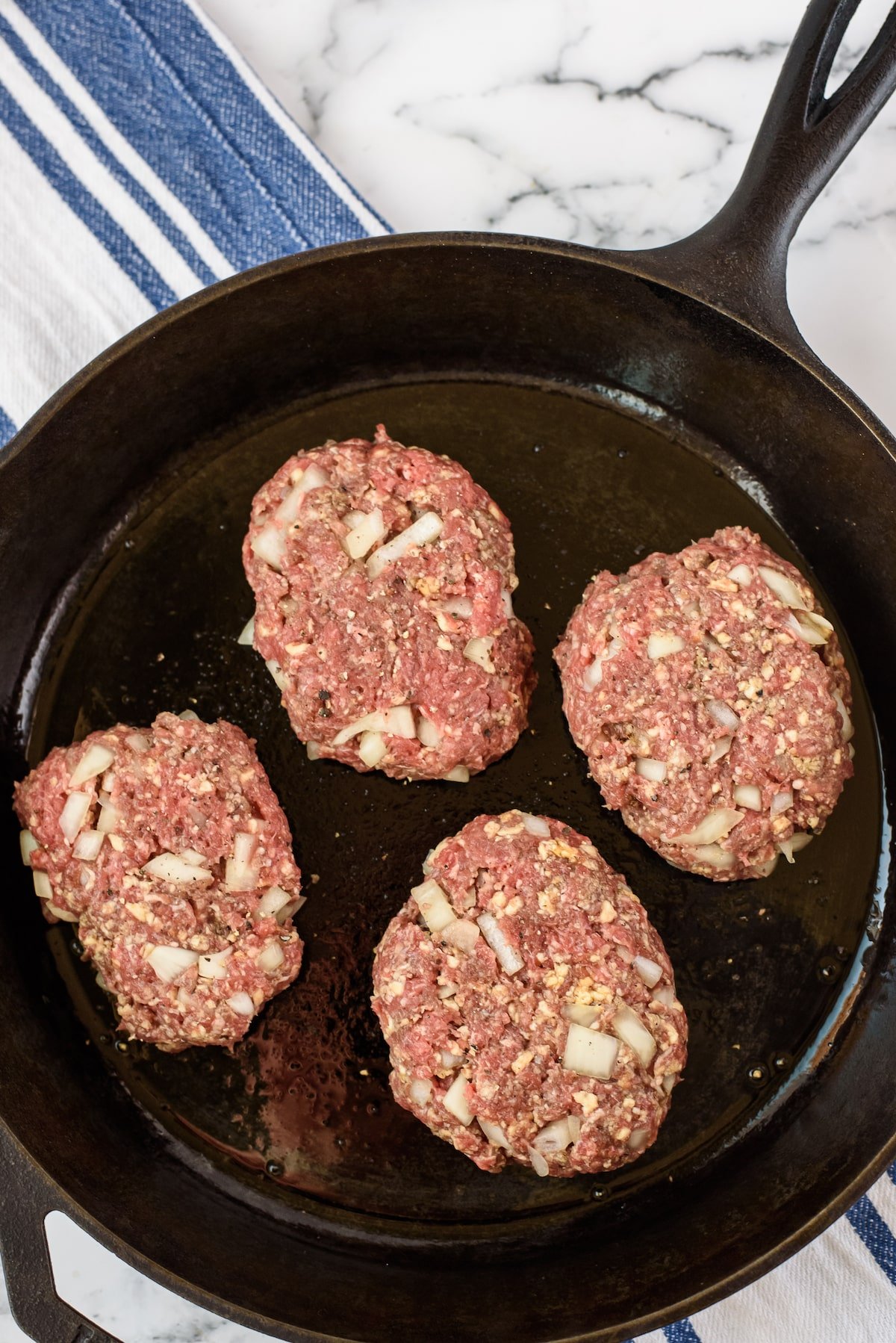 four steaks in sauce in a black pan.