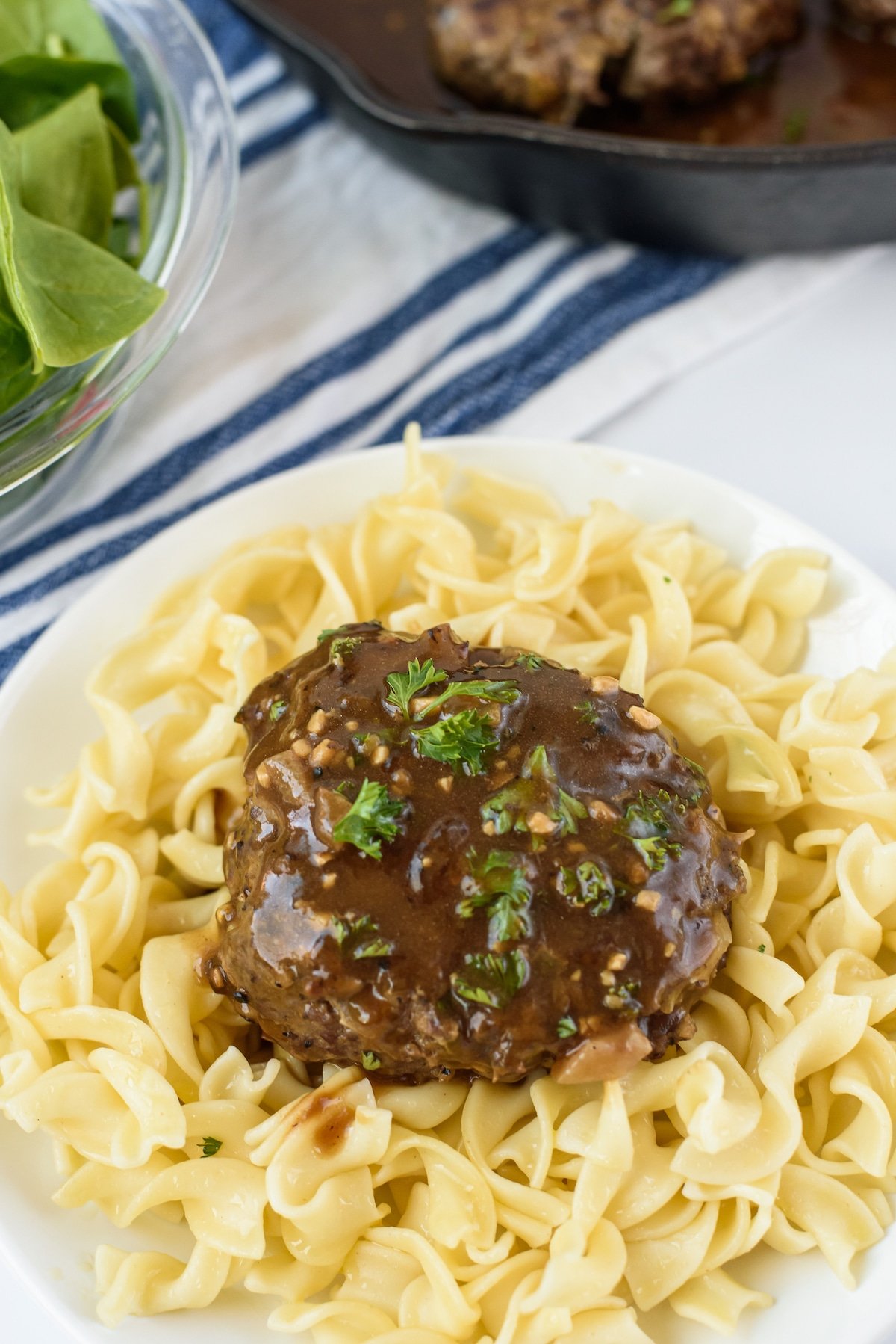 steak on top of pasta and covered in sauce.