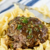 steak on top of pasta and covered in sauce.