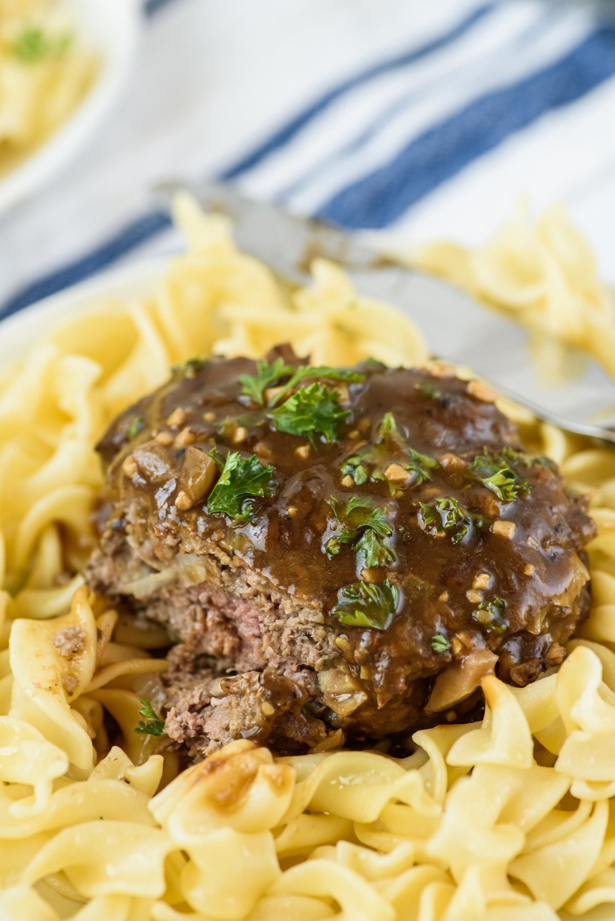 steak on top of pasta and covered in sauce.