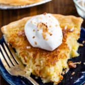 slice of coconut pie on a blue plate with whipped cream on top.