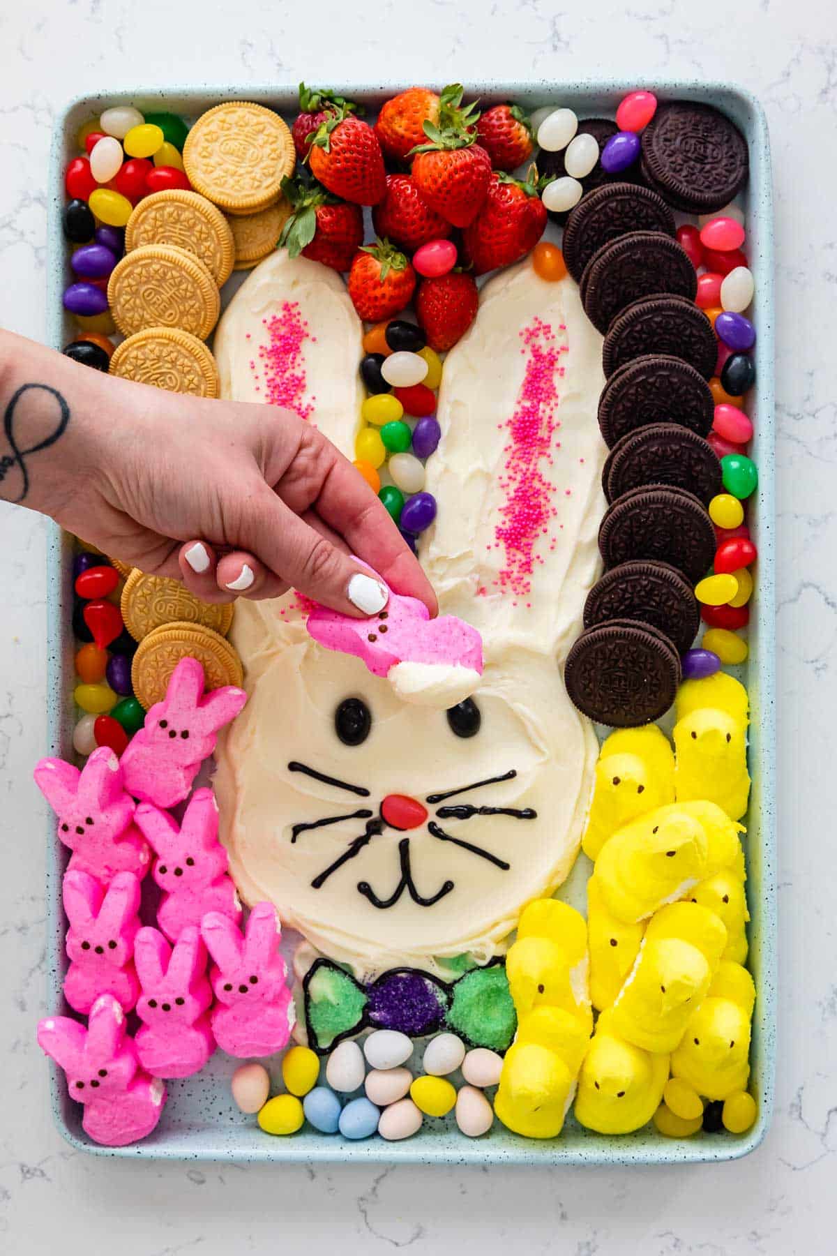 bunny shaped out of frosting and surrounded by jelly beans, marshmallows and oreos.
