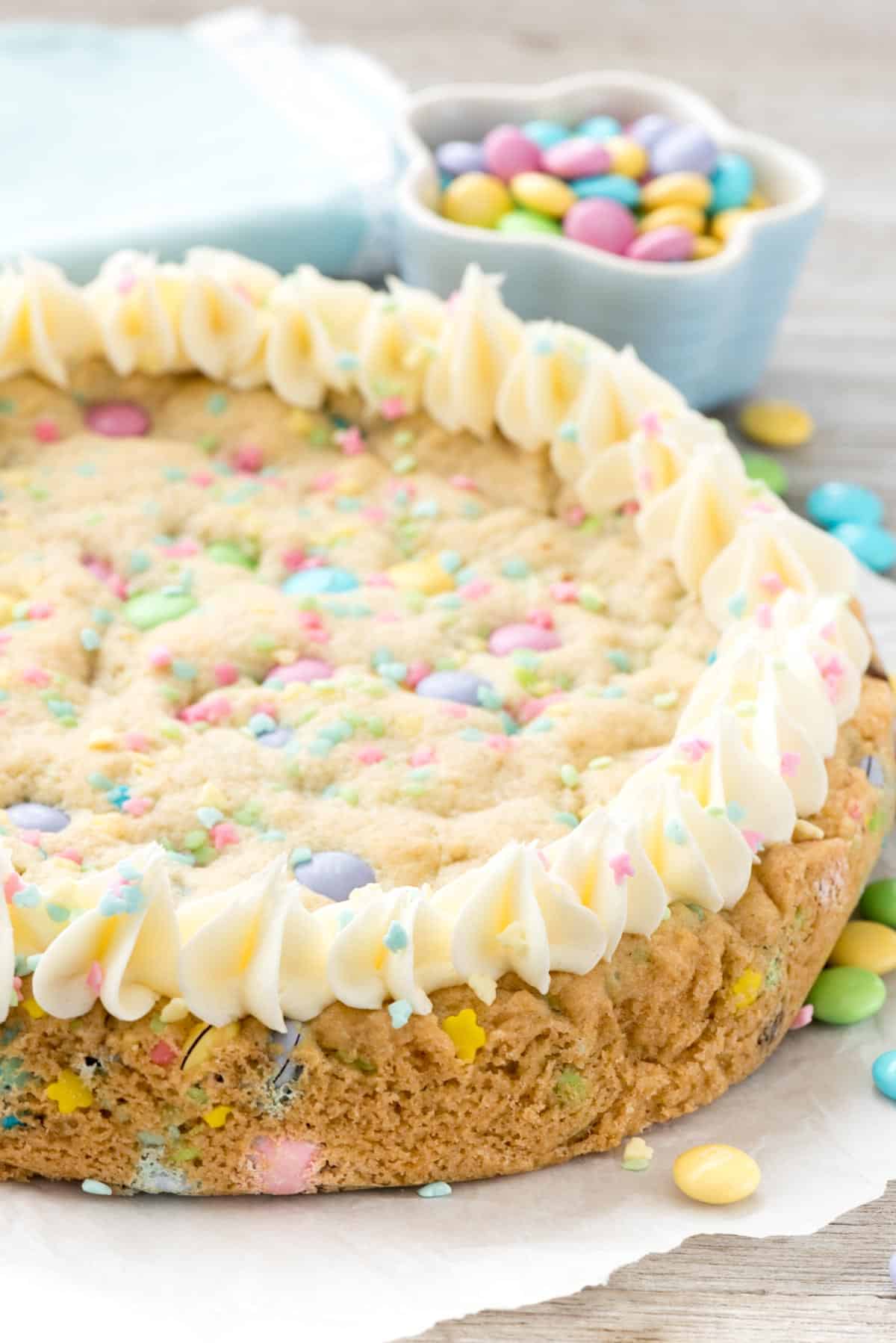 sugar cookie cake with frosting around the edge on parchment.