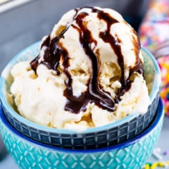 ice cream in blue bowls with chocolate sauce drizzled over the ice cream.