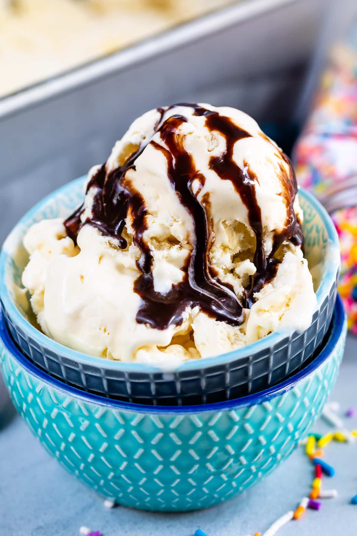 ice cream in blue bowls with chocolate sauce drizzled over the ice cream.