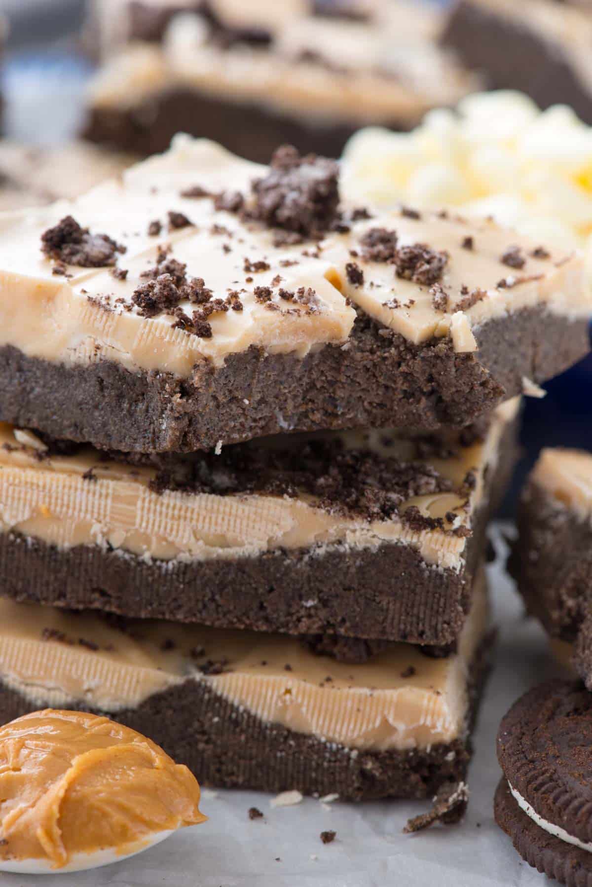 stacked chocolate and peanut butter layer bars with oreo crumble on top.