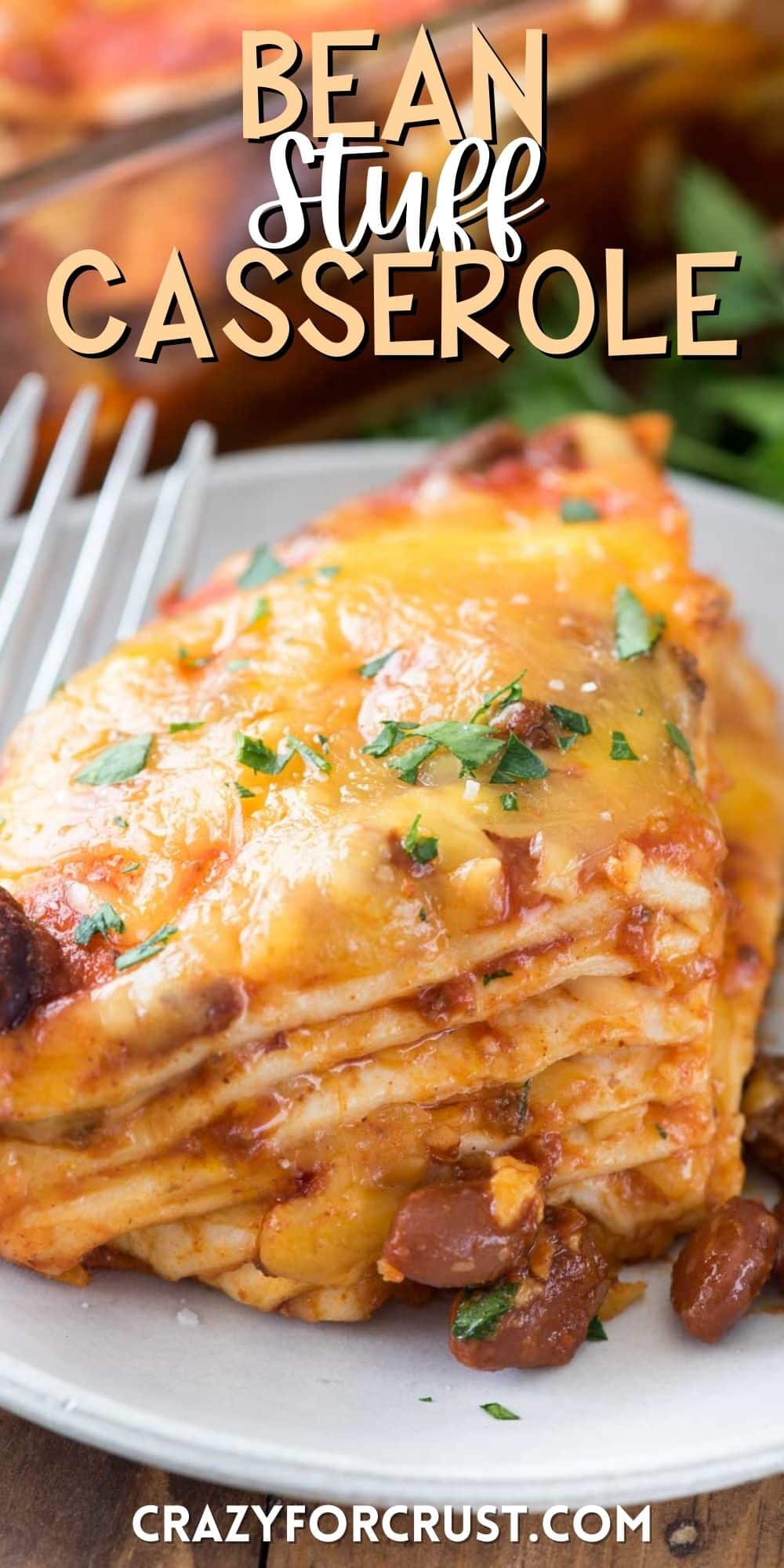 layered bean casserole on a white plate next to a fork with words on the image.