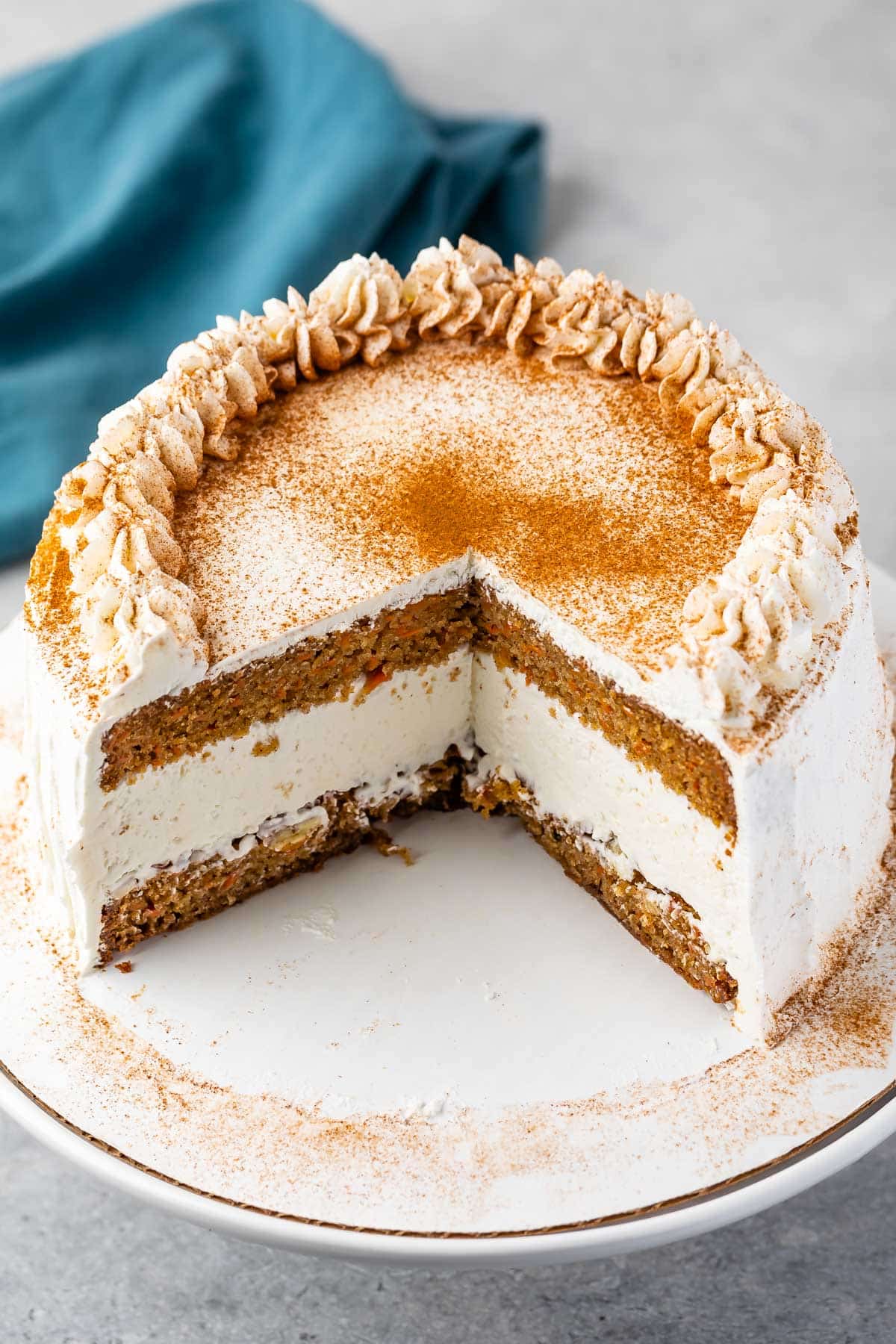 carrot cake covered in white frosting and cinnamon.