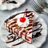 pink slice of pie covered in chocolate sauce, whipped cream and a cherry.