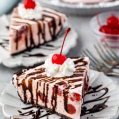 pink slice of pie covered in chocolate sauce, whipped cream and a cherry.