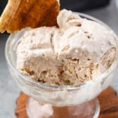 ice cream scooped into clear ice cream bowl and a churro piece mixed in.