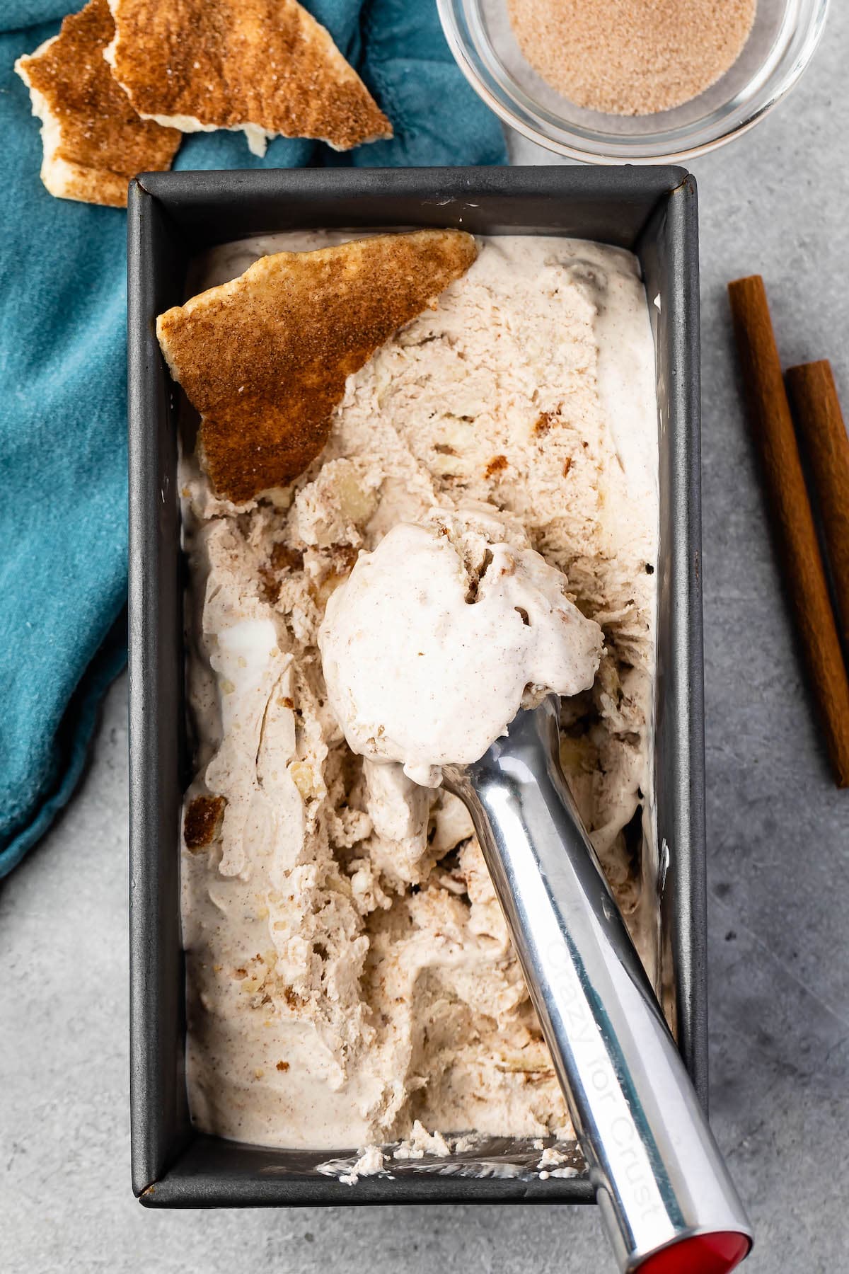 ice cream in grey tin with an ice cream scooper in the tin.