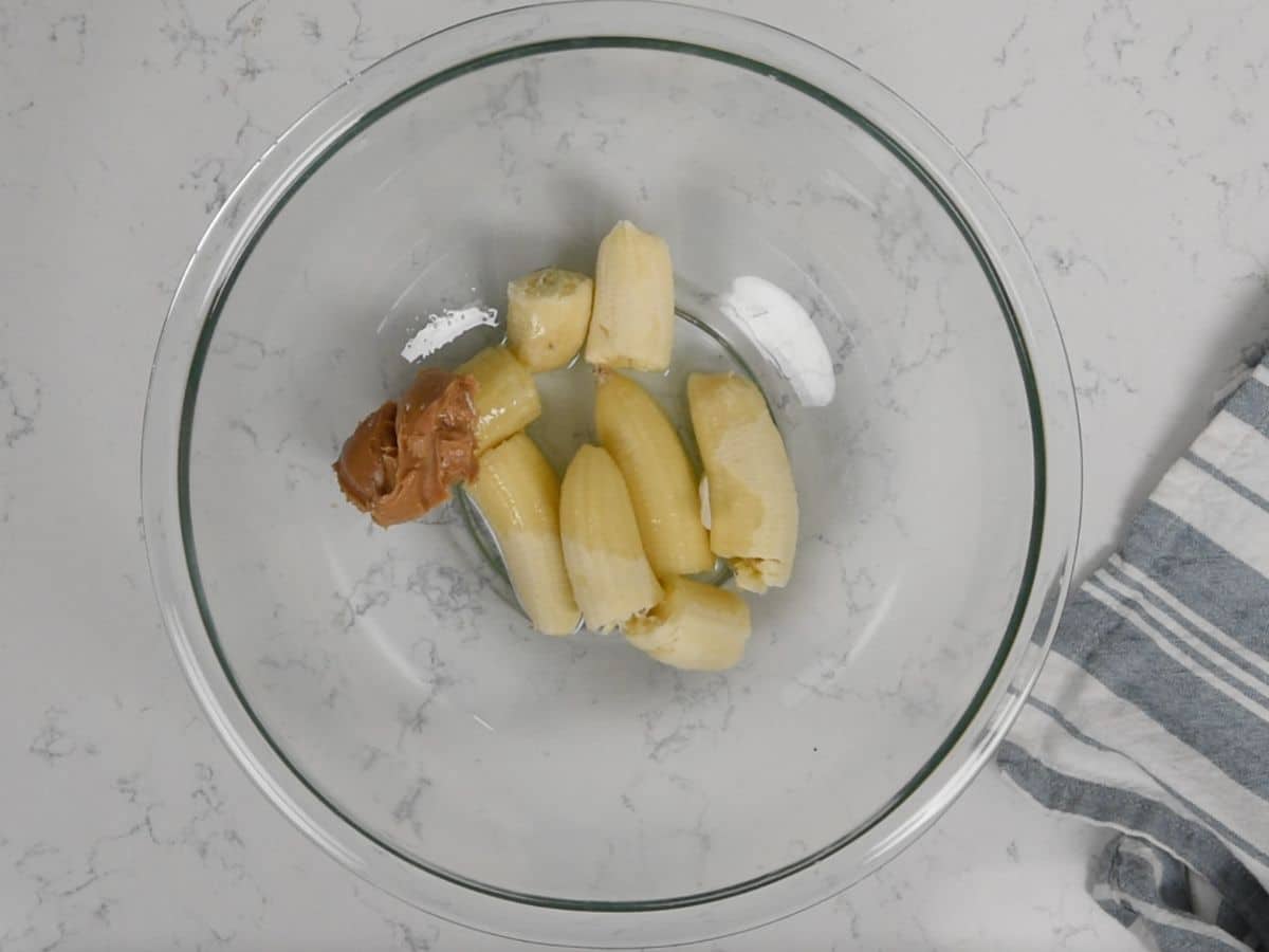 bananas, oil, peanut butter in clear bowl.