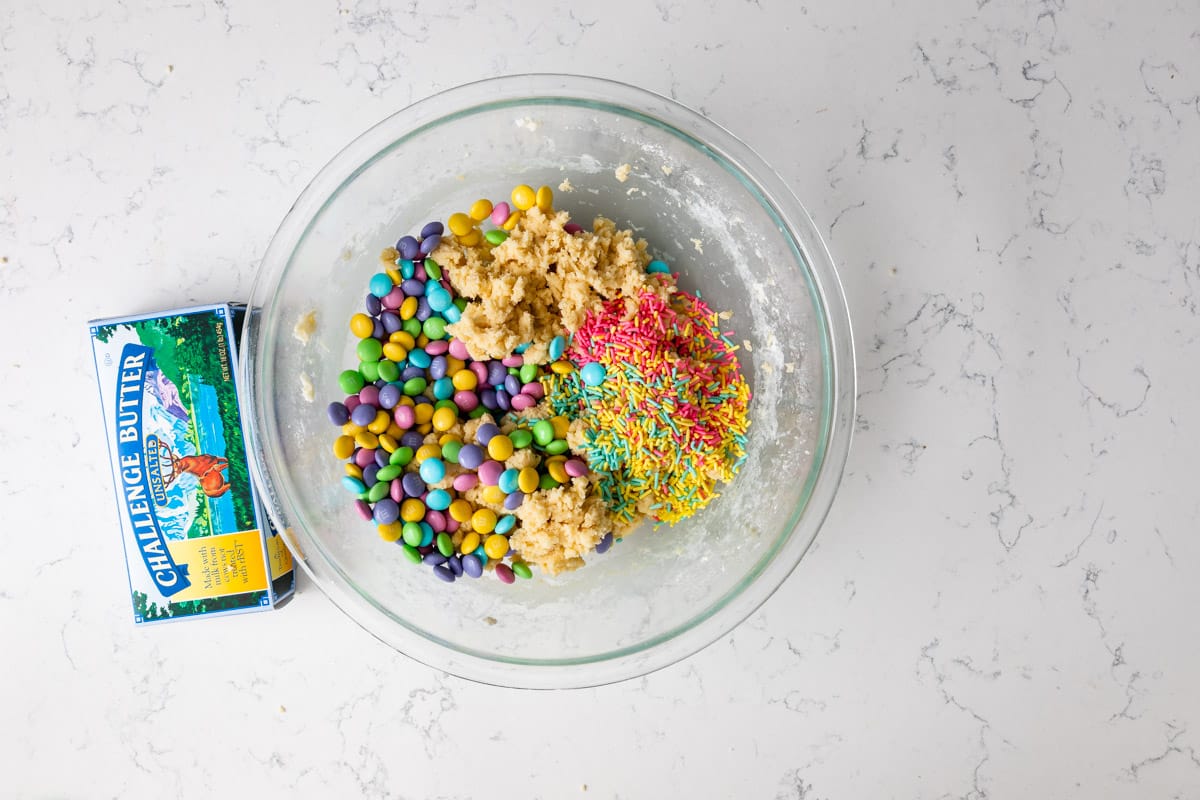 dough in bowl with m&ms and sprinkles with butter box.