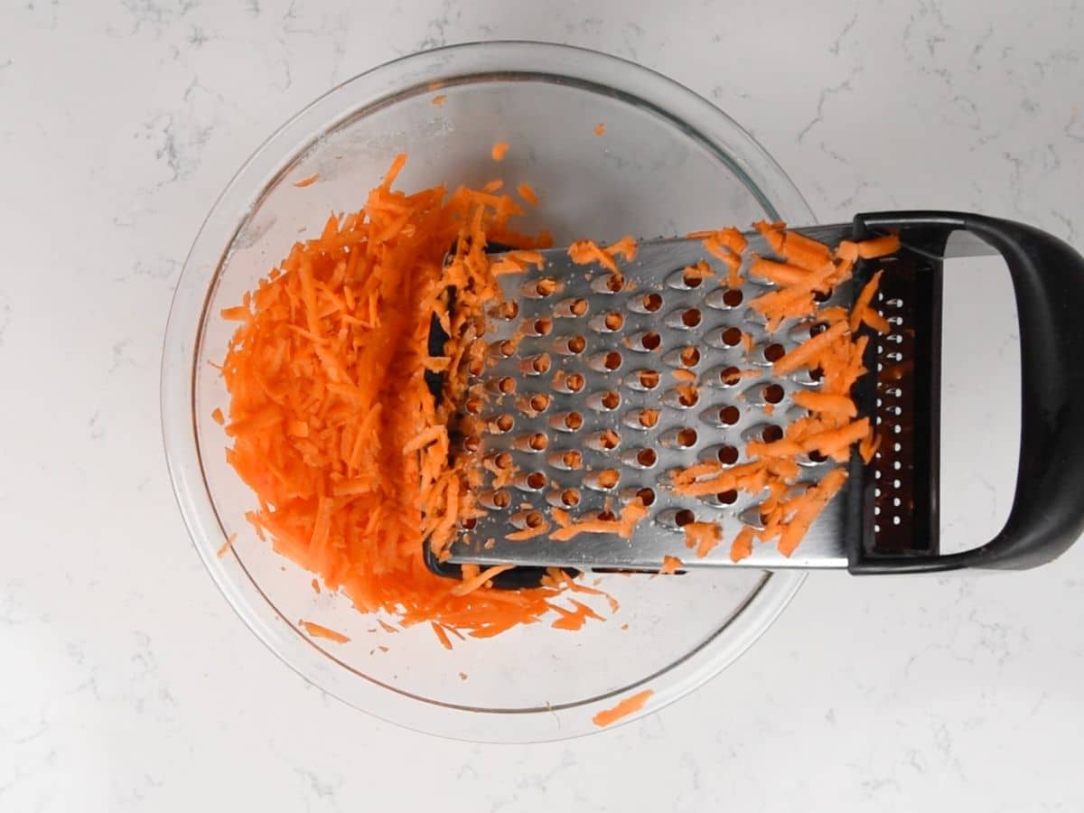 grater in bowl of shredded carrots.