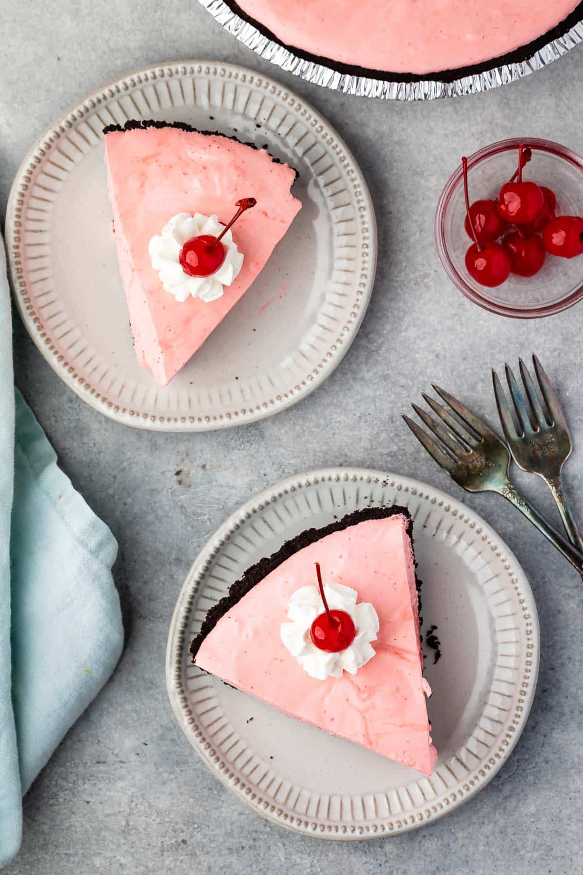 slice of pink pie on oreo crust with whipped cream and a cherry on top.