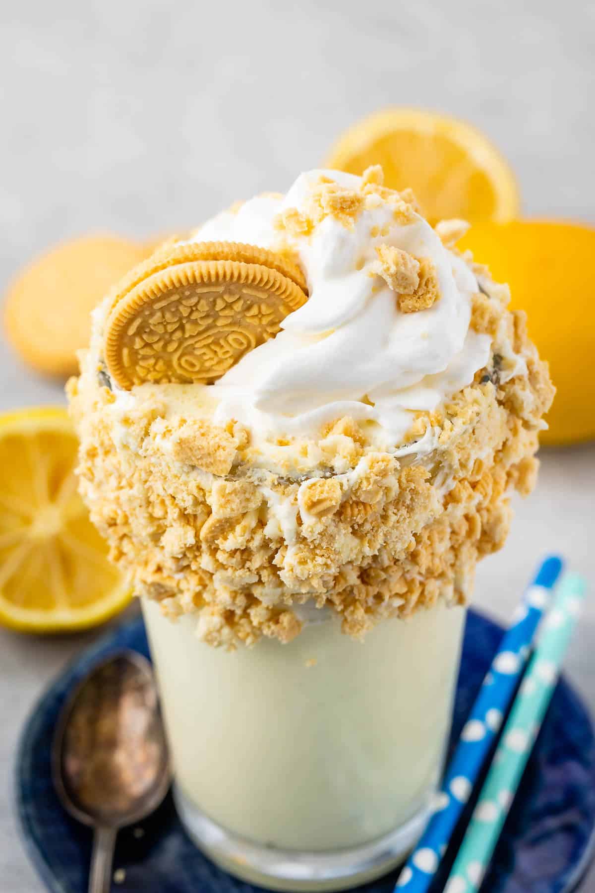 lemon milkshake in a clear glass and crushed golden oreos around the rim of the glass.