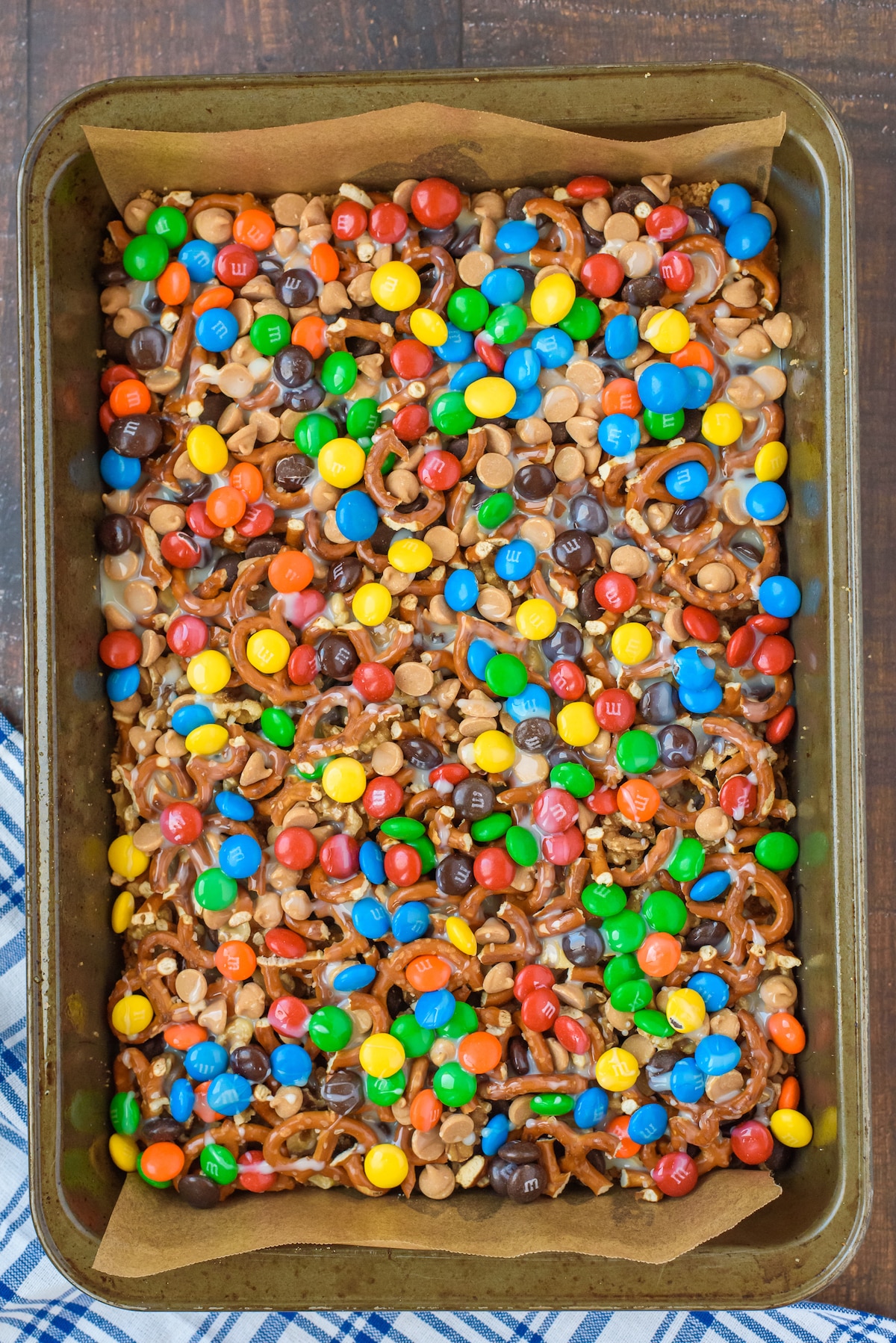 magic bars with nuts, pretzels and m&ms on top.