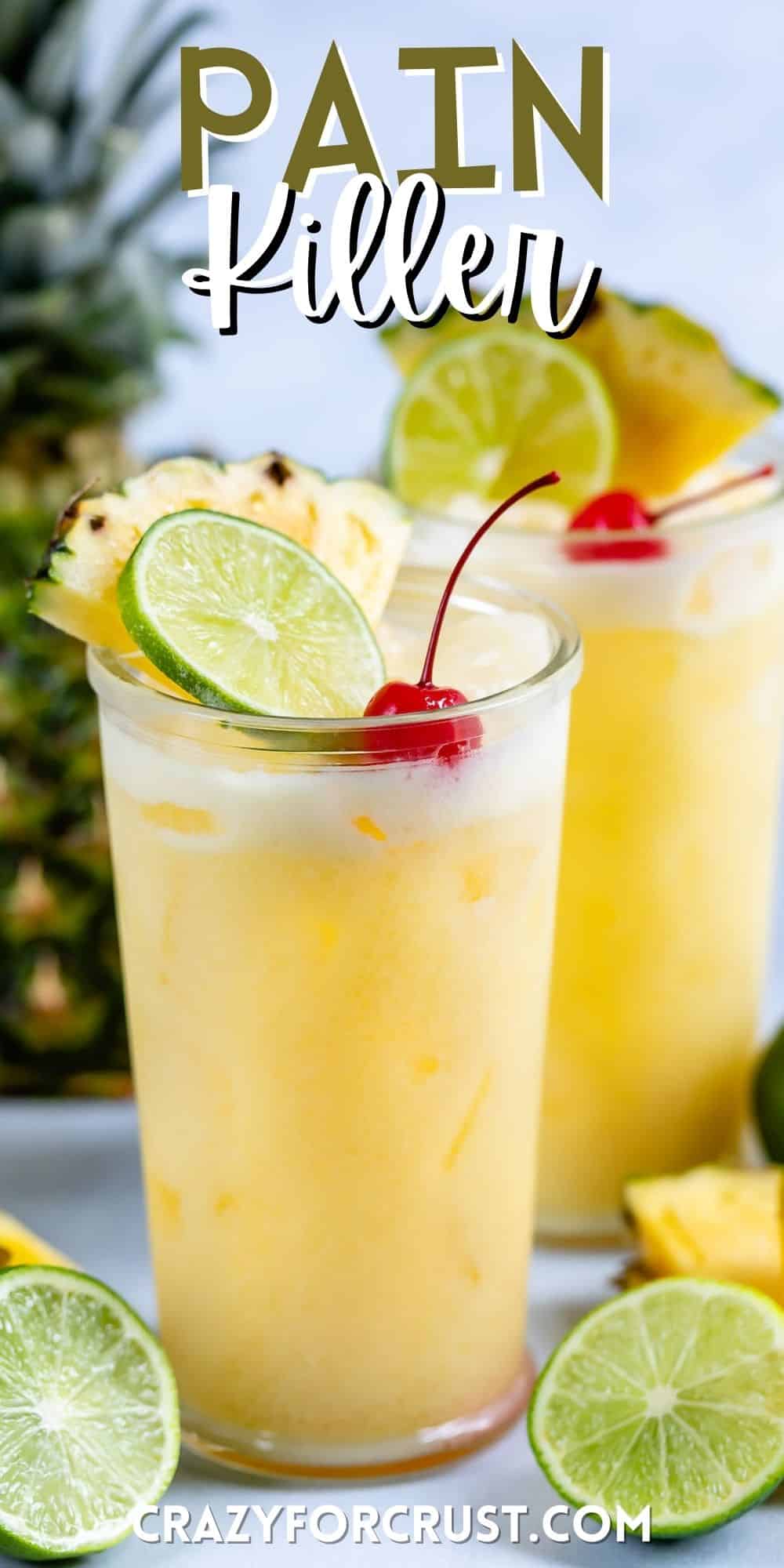 yellow cocktail in a clear glass with a cherry, lime and pineapple slice in the drink with words on the image.