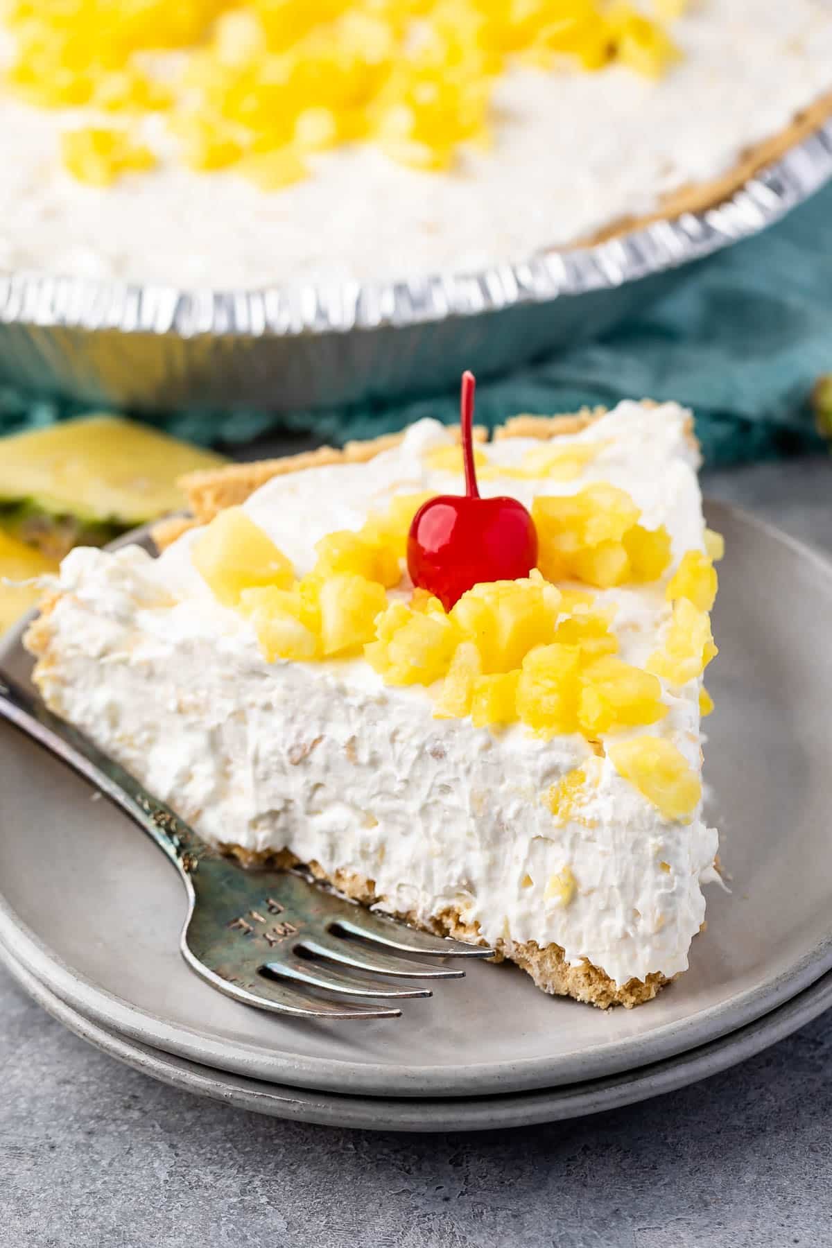 pie with a graham cracker crust and pineapple and a cherry on top.