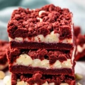 stacked red velvet gooey bars with white chocolate chips sprinkled around.