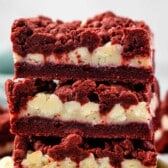 stacked red velvet gooey bars with white chocolate chips sprinkled around.