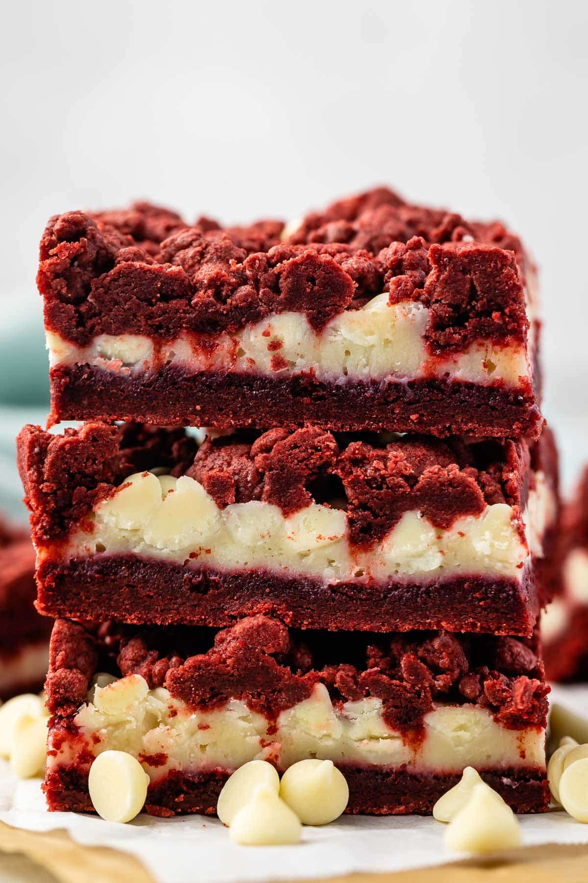 stacked red velvet gooey bars with white chocolate chips sprinkled around.