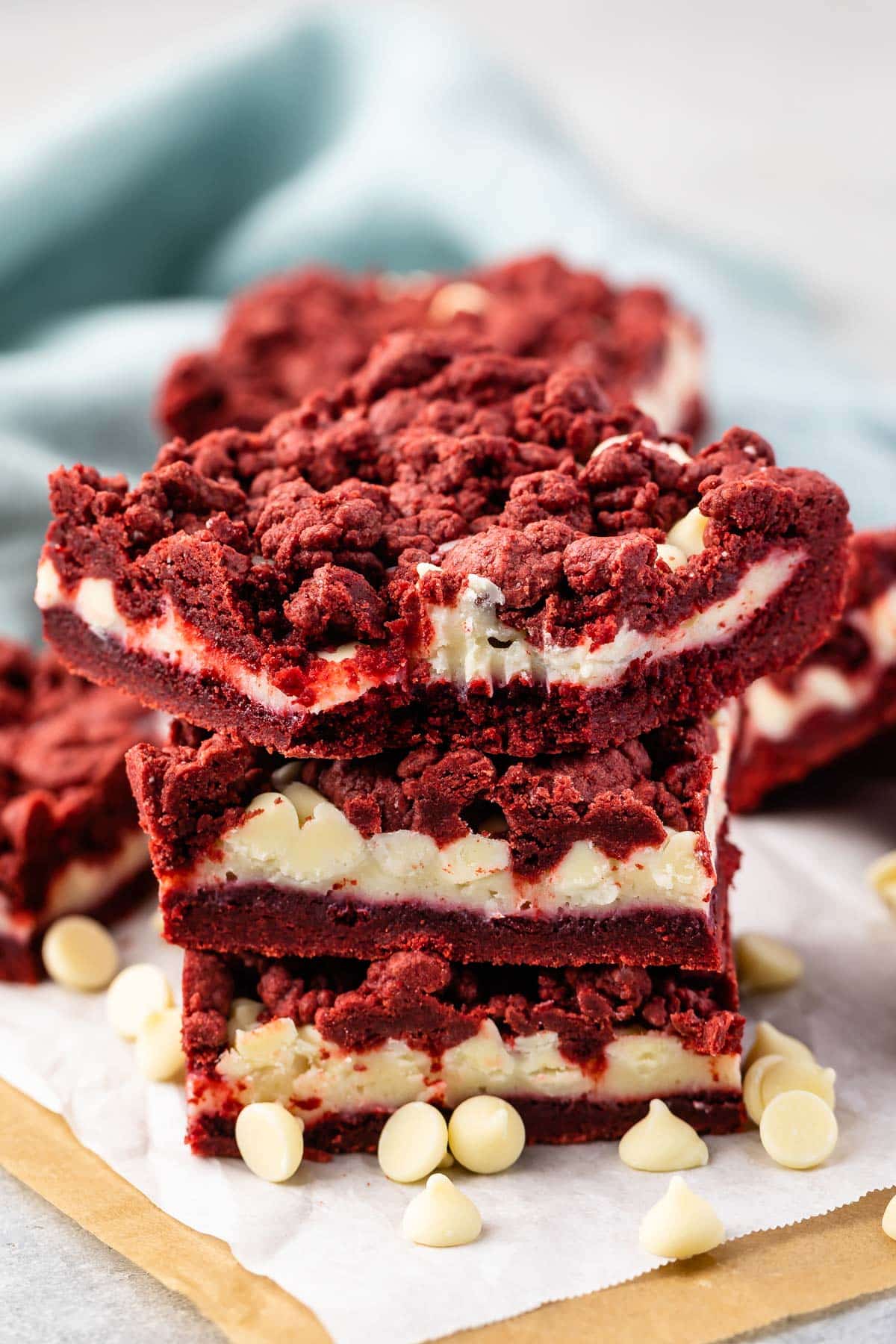 stacked red velvet gooey bars with white chocolate chips sprinkled around.