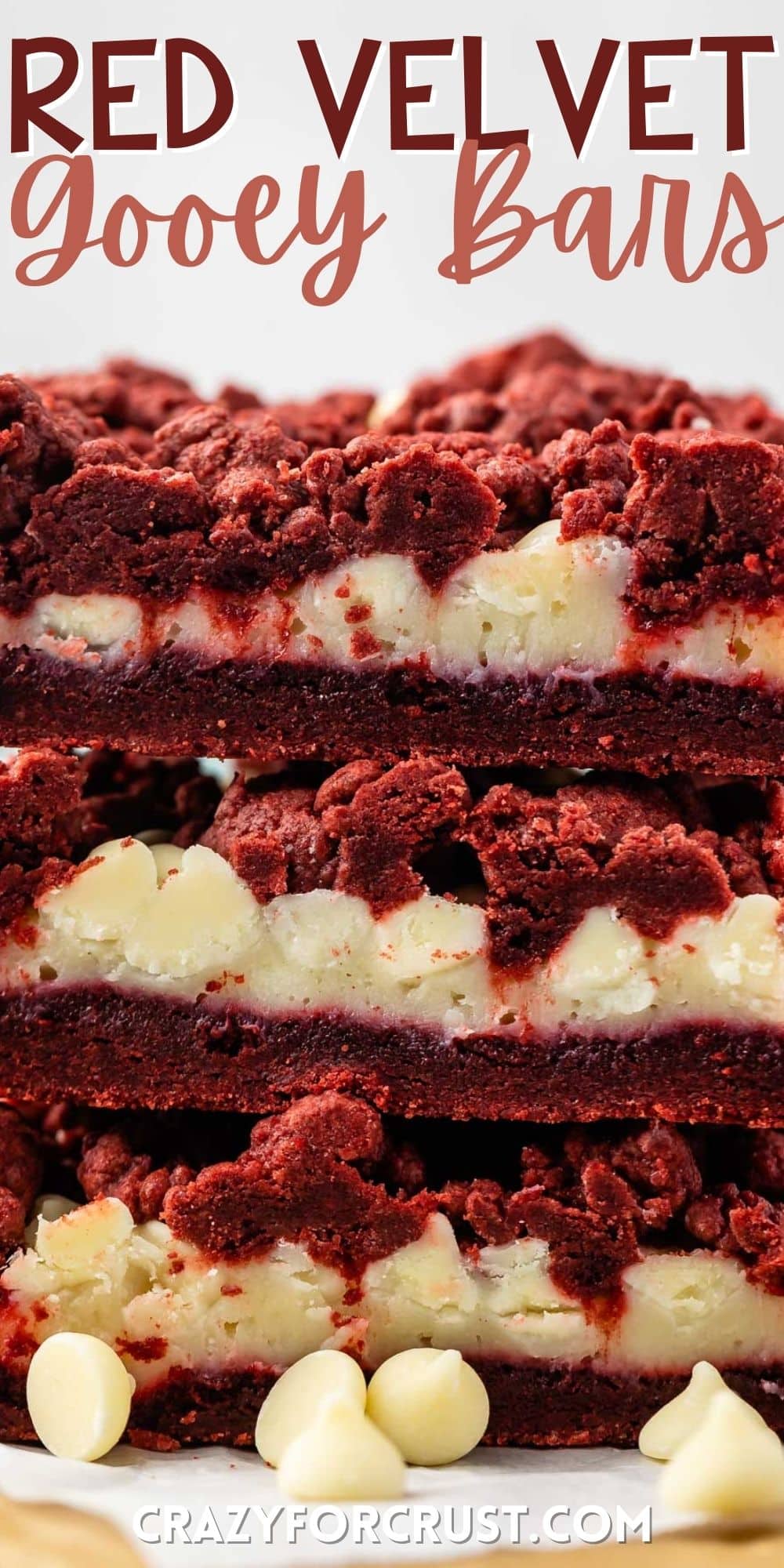 stacked red velvet gooey bars with white chocolate chips sprinkled around with words on the image.