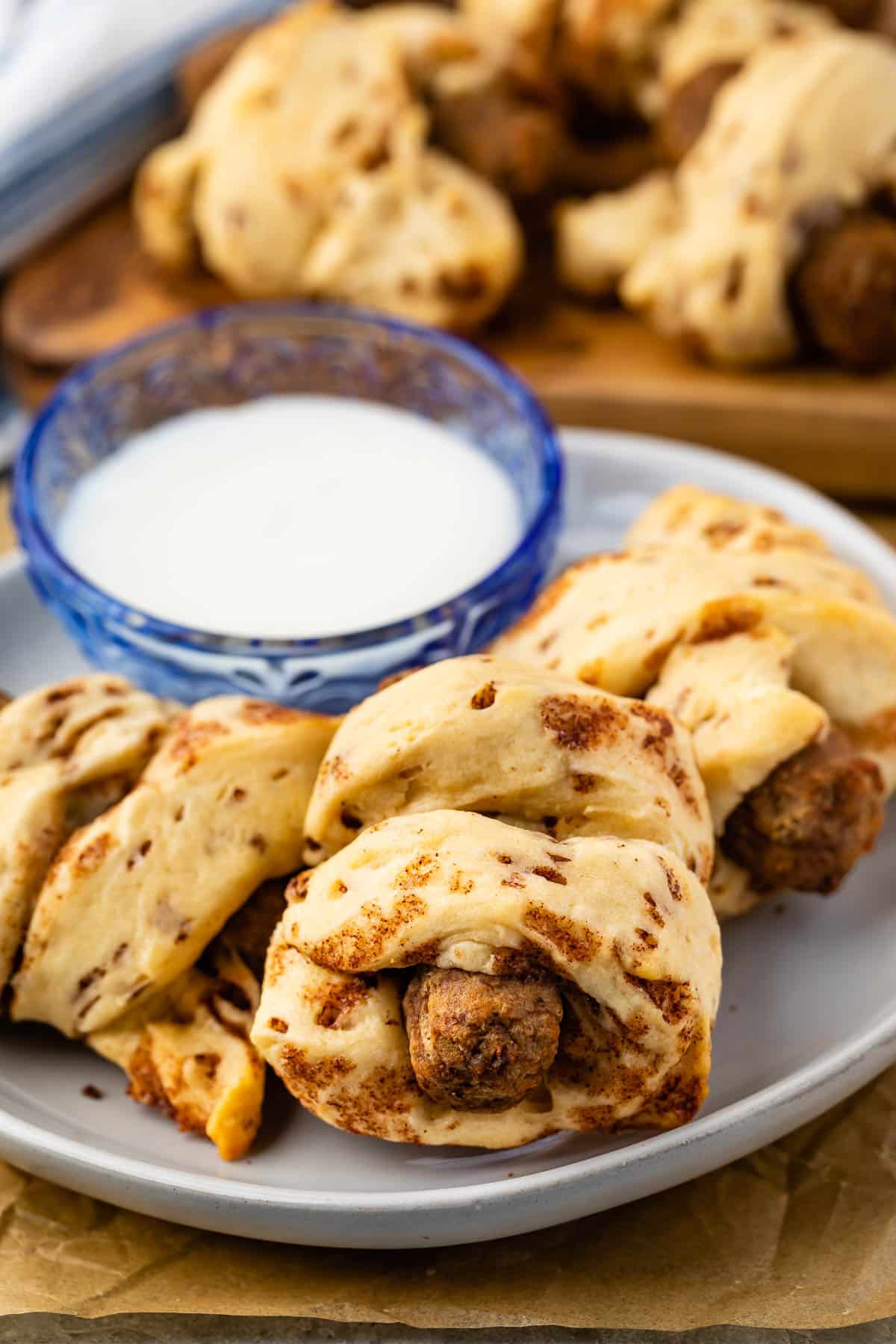 sausage wrapped in cinnamon rolls on a grey plate.