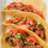 shredded beef in a tacos mixed with tomatoes.
